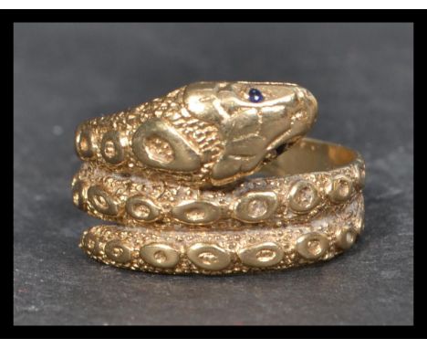 A hallmarked vintage 9ct gold ring in the form of a coiled snake having sapphire eyes. Hallmarked worn.Tests 9ct gold. Weight