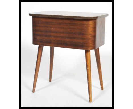 A vintage retro 20th century teak sewing box raised on tapering legs with hinged lid opening to reveal a quantity of sewing e
