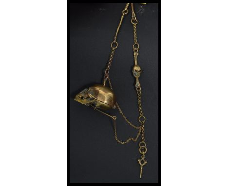 A brass novelty anatomical Albert fob chain in the form of a skull and bones with hand and bone links. The skull opening for 