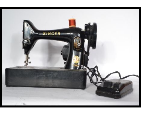 A mid 20th Century vintage based electric Singer sewing machine. The machine painted in typical black with gilt embellishment