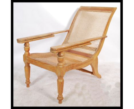 A 20th Century vintage hardwood Plantation chair / armchair with 2 slide out arms being raise on turned legs with a bergere c