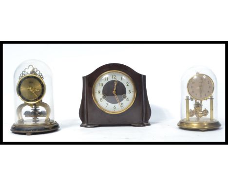 A collection of clocks to include a Schatz brass anniversary clock, a Bentimo anniversary clock, both under domes together wi