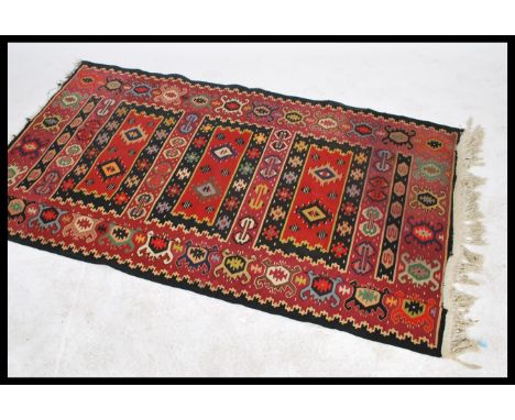 A vintage 20th century floor rug having a run of three central rectangular geometric panels within stylised geometric panel o