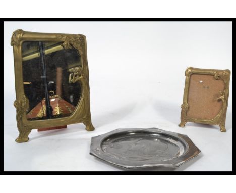 A graduating pair of Art Nouveau gilt brass easel back picture frames modelled with floral sprays and figures. Along with an 