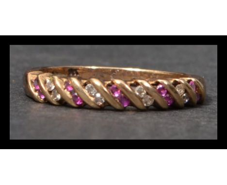 A hallmarked 9ct gold ruby and diamond band ring having round cut rubies and diamonds in a raised lattice style setting. Hall