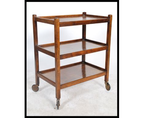 A vintage early 20th century / 1930's oak 3 tier trolley being raised on the original castors having squared columns to corne