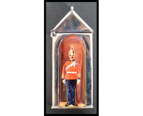 A sterling silver vesta case in the form of a sentry box with enamel panel depicting a guard. Weighs 35 grams.