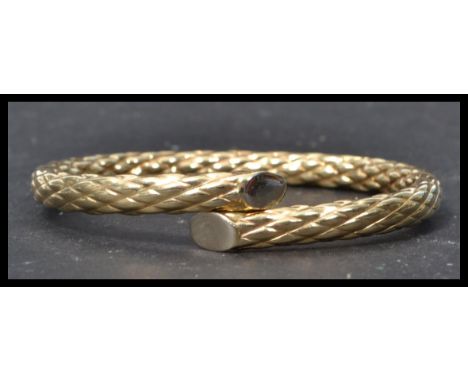A hallmarked 9ct gold crossover bangle bracelet having a diamond cut design. Hidden split open clasp hinge for ease of wearin