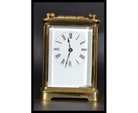 An early 20th century brass carriage clock with inset brass movement. Enamel face with roman numeral chapter ring and faceted