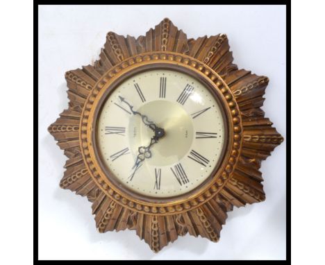 A vintage mid 20th century retro Smiths sunburst wall clock. The two tone dial having Roman numerals with faceted hands. Set 
