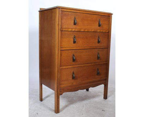 A vintage mid 20th Century oak straight chest of four graduating drawers, fitted with brass handles and raised on square legs