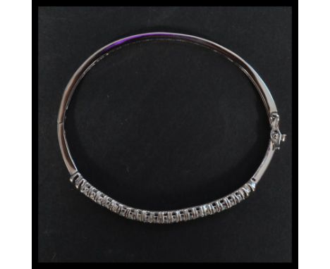 A sterling silver and CZ bangle bracelet having two lined of white CZ stones with hidden clip clasp.