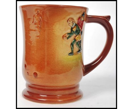 A Royal Doulton tankard having polychrome decoration in relief depicting Francis Drake playing bowls on a two tone brown grou