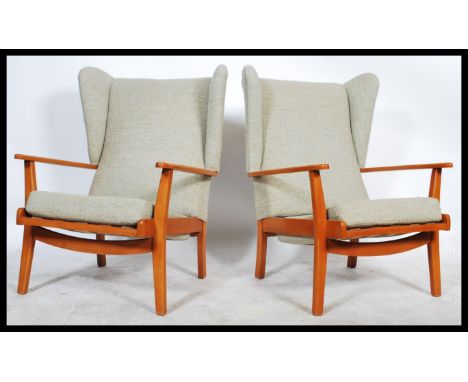 A 1970's retro vintage teak wood wingback three piece suite comprising of a pair of wingback armchairs and a two seater&nbsp;