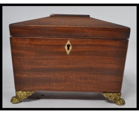 A good Georgian 19th century mahogany tea caddy of sarcophagus form having brass hairy paw feet with hinged top and appointed