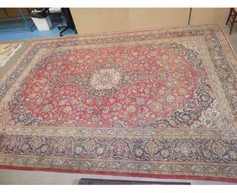 A large middle eastern style carpet, central medalion within red foliate panel and multiple foliate decorated borders 4.1m x 