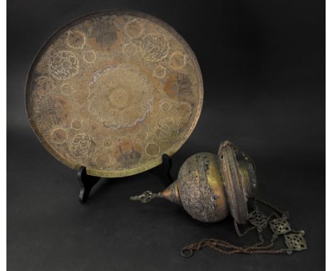 An Islamic circular brass dish, engraved with four vignettes of buildings reserved against a foliate ground enclosing a large