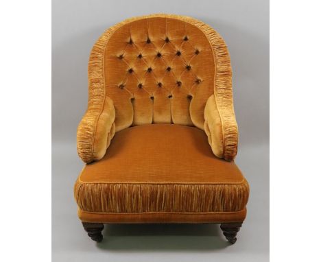 A late Victorian button down upholstered armchair, in old gold velour, with ruched borders, having an arched back, on turned 
