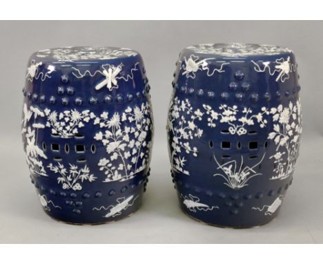 A pair of Chinese blue ground barrel shaped garden seats, circa 1900, painted in thick white enamel with birds in branches an