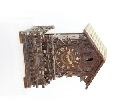 A BLACK FOREST CUCKOO CLOCK of architectural form, with carved fruiting vine decoration to the front and balcony, 26cm wide x