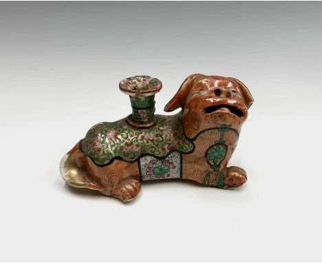 A Chinese Canton porcelain lion dog candlestick holder, 19th century, wearing a lotus flower gilt decorated saddle cloth and 