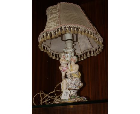 A CONTINENTAL PORCELAIN FIGURATIVE TABLE LAMP, modelled as a lady holding a child on a gilt lined and floral encrusted base, 