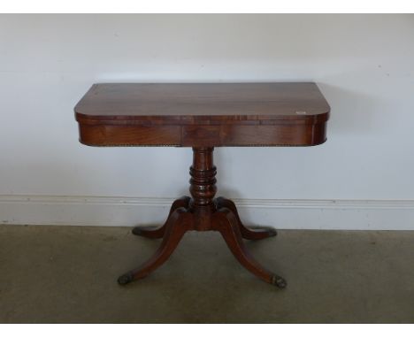 A Regency rosewood card table on quatrefoil base with single turned column terminating in brass paw feet - 91.5cm x 90cm x 71