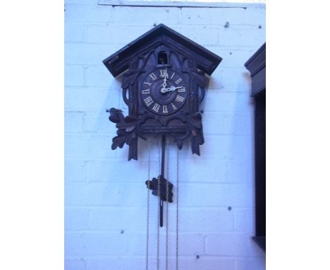 A carved wooden cuckoo clock with pendulum and weights - 37cm x 26cm