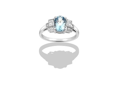 An Aquamarine and Diamond Ringthe oval cut aquamarine in white claw settings, flanked by trios of baguette cut diamonds in mi