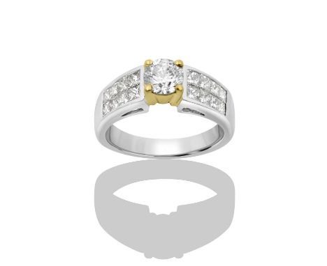 An 18 Carat White Gold Diamond Ringthe round brilliant cut diamond in a yellow claw setting, to princess cut diamond set shou