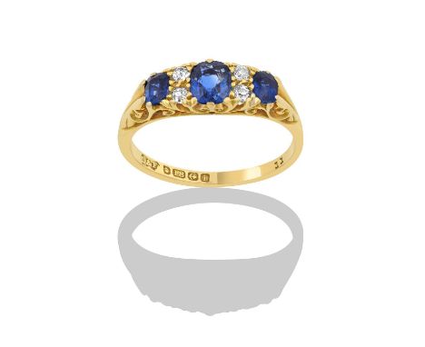 An 18 Carat Gold Sapphire and Diamond Ringthree graduated oval cut sapphires spaced by pairs of old cut diamonds, in yellow c