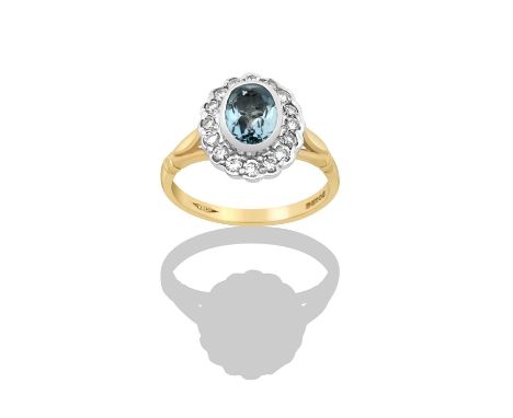 A 9 Carat Gold Aquamarine and Diamond Cluster Ringthe oval cut aquamarine in a white rubbed over setting, within a border of 