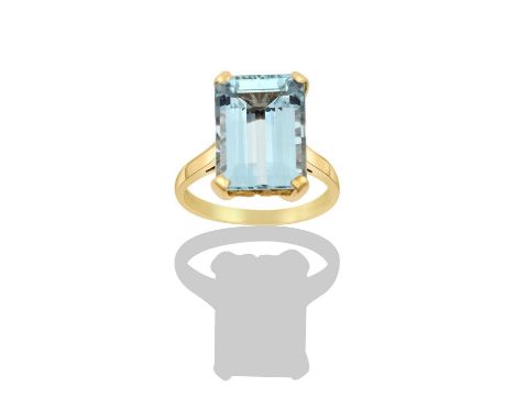 An Aquamarine Ringthe emerald-cut aquamarine in a yellow four claw setting, to a tapered shoulder plain polished shankfinger 