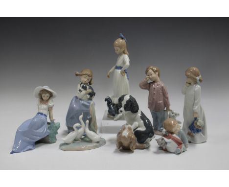 Eight Nao figures, including a boy with teddy bear, two playful spaniels, a girl sitting beside a bird and a girl standing be