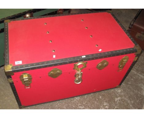 Vintage red canvas trunk with carrying handles and metal and brass banding.
