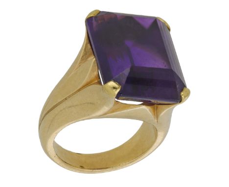 An amethyst dress ring, the rectangular step-cut amethyst claw-set between tapering stylised foliate shoulders, ring size K. 