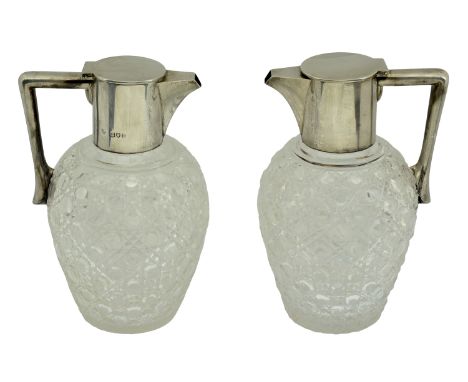 A matched pair of Edward VII silver mounted cut-glass claret jugs, the spouts and lids of plain design, with angular handles,