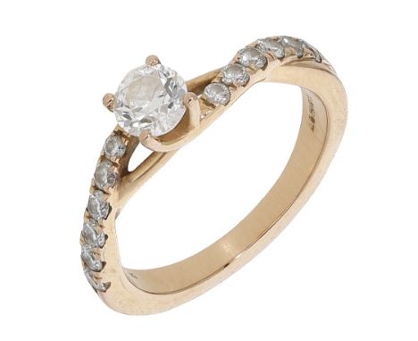A diamond ring, of crossover design, the principal brilliant-cut diamond between similarly-set diamond shoulders, mounted in 