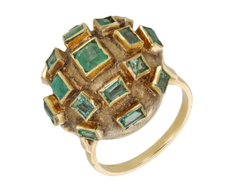 An emerald dress ring, of textured bombé form, collet-set throughout with step-cut emeralds, stamped ‘18K’, ring size N. £300