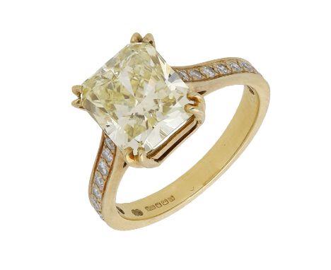 A Fancy Yellow diamond ring, the cut-cornered Fancy Yellow diamond, weighing 4.13 carats, between shoulders set with brillian