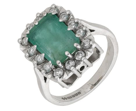 An 18ct white gold emerald and diamond cluster ring, the step-cut emerald claw-set within a surround of brilliant-cut diamond