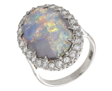 A black opal and diamond cluster ring, the opal cabochon claw-set within a surround of brilliant-cut diamonds, the shank stam