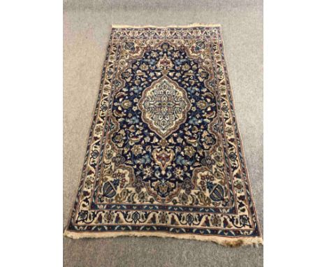 Carpet, Kashan with central medallion on a midnight ground within foliate spandrels and multiple borders. L.195 W.103cm. 