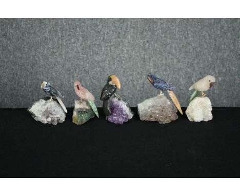 A collection of five pieces of amethyst mounted with detachable perched parrots carved from various stones. The birds are wel
