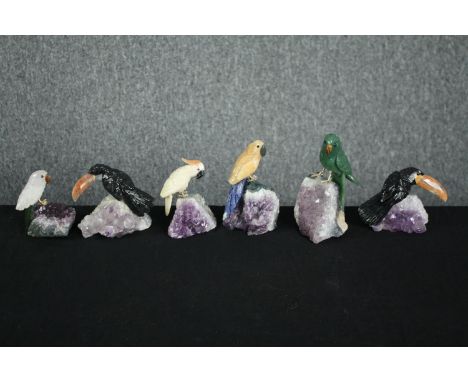 A collection of six pieces of amethyst mounted with detachable perched parrots carved from various stones. The birds are well