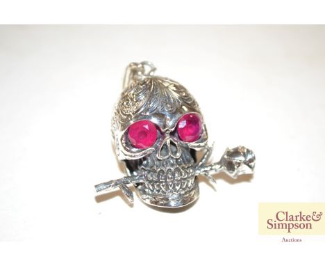 A silver and ruby type skull and rose pendant 