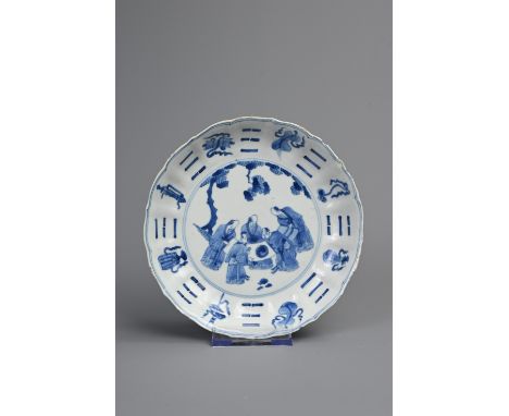 A CHINESE BLUE AND WHITE PORCELAIN DISH, EARLY 18TH CENTURY. Of lobed form decorated with scholars admiring a Yin Yang scroll