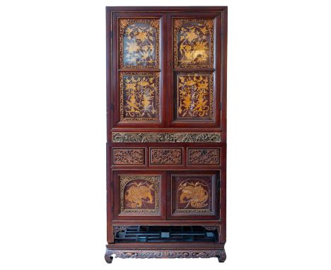 A 20TH CENTURY CHINESE CARVED GILTWOOD AND RED STAINED CABINET ON STAND. The glazed double doors carved with birds amongst fl