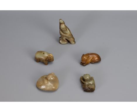 FIVE CHINESE CARVED JADE PENDANTS, of different forms to include a recumbent lion, Liu Hai, recumbent dog, a boy and an eleph