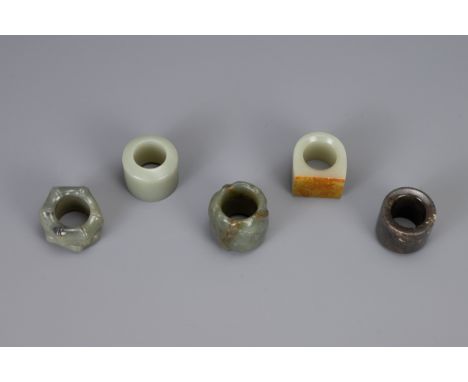 FIVE CHINESE CARVED JADE ARCHERS RINGS, to include bamboo form, lotus form, and three others, largest diameter approx. 4 cm (